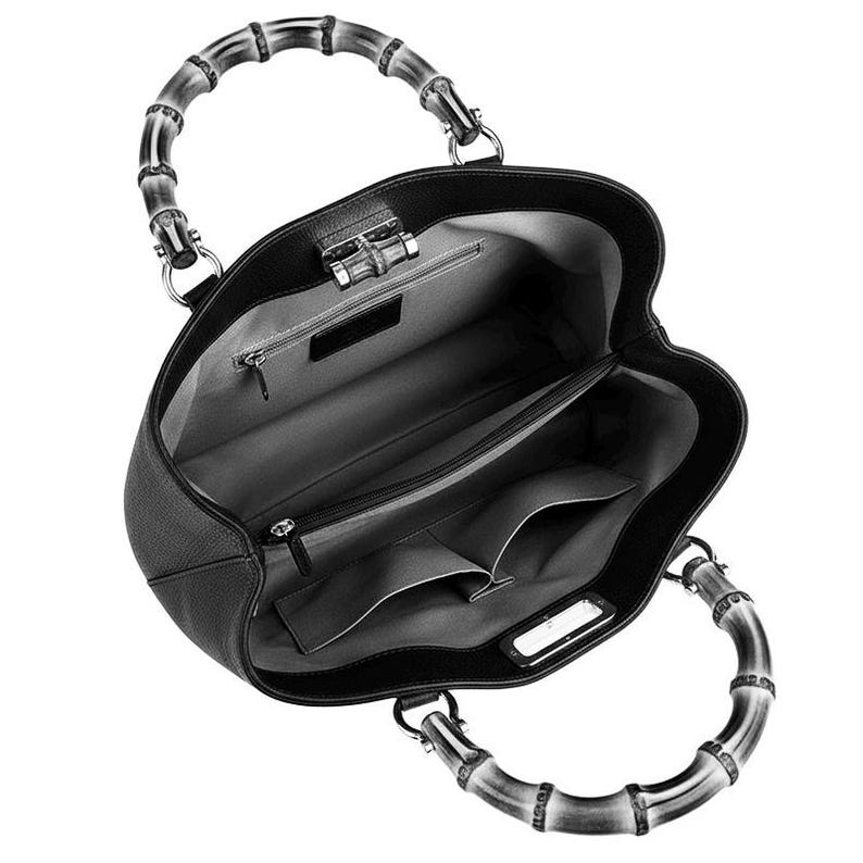 May include: A black leather handbag with a textured surface and two curved bamboo handles. The interior is lined with grey fabric and features a central zippered compartment, two open slip pockets, and a small zippered wall pocket.