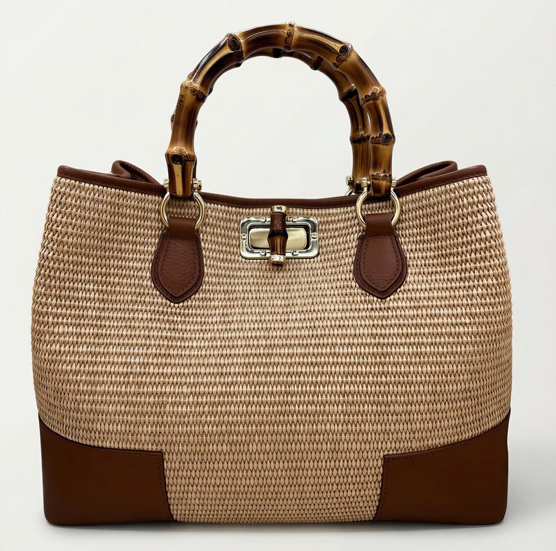 Pode incluir: Uma bolsa tote de palha tecida com uma al&ccedil;a de bambu. A bolsa apresenta detalhes em couro marrom na base e na borda, com um fecho dourado. A al&ccedil;a &eacute; feita de bambu curvo.