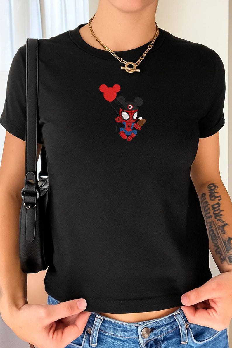 May include: Black t-shirt featuring a cartoon mashup of Spider-Man and Mickey Mouse holding a red balloon and a small treat. The graphic is in red, blue, and black. The shirt has short sleeves and a crew neck.
