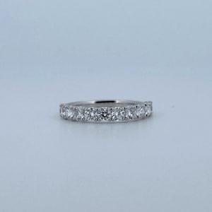 Puede incluir: Un anillo de plata con una fila continua de piedras preciosas redondas y claras. El anillo est&aacute; engastado sobre un fondo azul claro, resaltando el brillo de las piedras. Un dise&ntilde;o cl&aacute;sico, adecuado para diversas ocasiones. El ancho del anillo es de aproximadamente 0,2 cm.