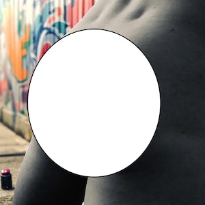 May include: A grayscale image featuring a person's torso, with a white circle obscuring the midsection. The background shows a colorful graffiti wall and a small, dark spray paint can.