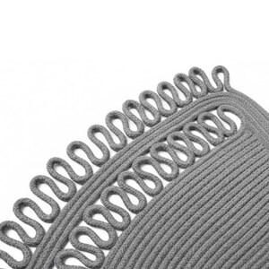 May include: Close-up of a gray, circular rug with a unique design. The rug features a looped border and a textured, braided pattern. The neutral color and simple design make it a versatile home decor item.