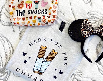 May include: A light gray t-shirt with the text "HERE FOR THE CHURROS" and a graphic of two churros, a zippered pouch with the text "I'M HERE FOR THE SNACKS" and snack icons, and a black headband with sequined ears and a leopard print bow.