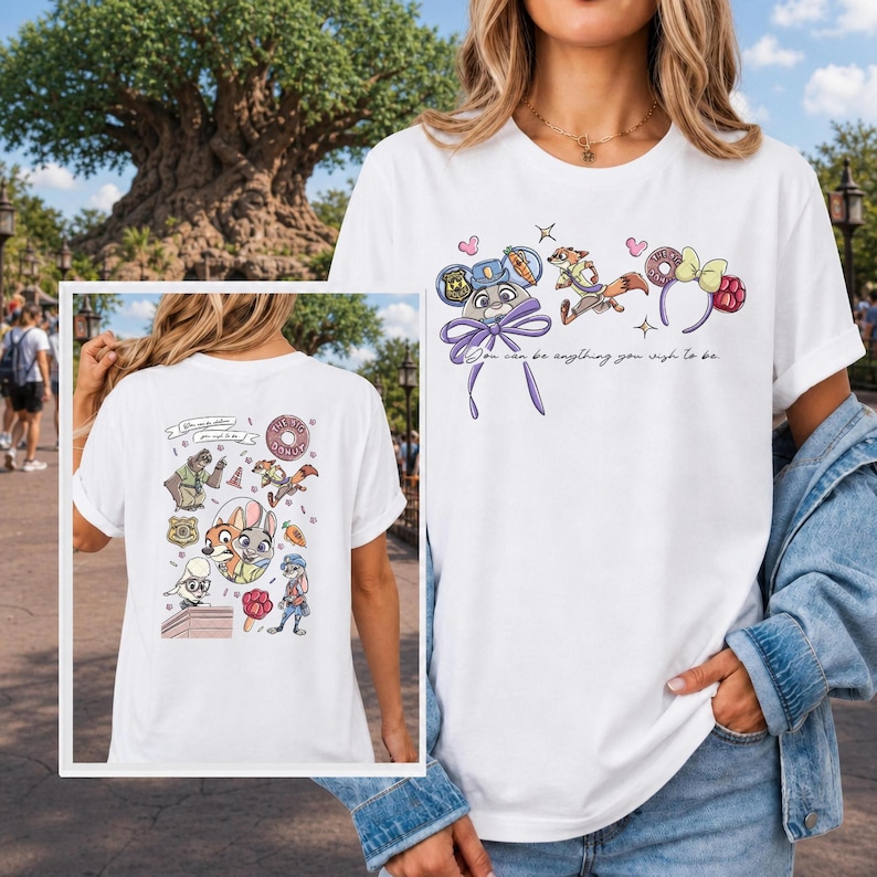 K&ouml;nnte beinhalten: Ein wei&szlig;es Kurzarm-T-Shirt mit Grafiken der Zootopia-Figuren und dem Text "You can be anything you wish to be." Das Design zeigt Illustrationen von Judy Hopps, Nick Wilde und Mausohren sowie eine detaillierte Collage auf der R&uuml;ckseite.