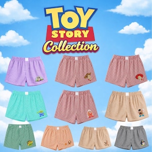 Puede incluir: Una colección de diez pares de calzoncillos tipo bóxer de cuadros vichy en varios colores, cada uno con un pequeño personaje bordado de la franquicia Toy Story. El logotipo Toy Story Collection aparece arriba sobre un cielo azul.