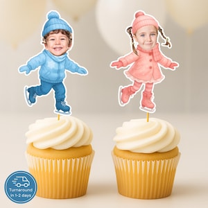 Op de afbeelding: Twee cupcakes met illustraties van kinderen die schaatsen. Het ene kind draagt ​​blauwe winterkleding, het andere roze. De cupcakes hebben witte glazuur en zitten in gele papieren vormpjes.