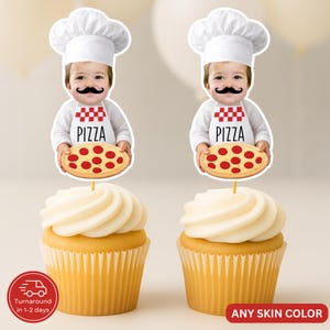 May include: Two cupcakes with white frosting, topped with pizza-themed toppers. The toppers feature a child dressed as a chef, holding a pizza. The child wears a chef's hat and an apron that says "PIZZA". The cupcakes sit in yellow paper cups.