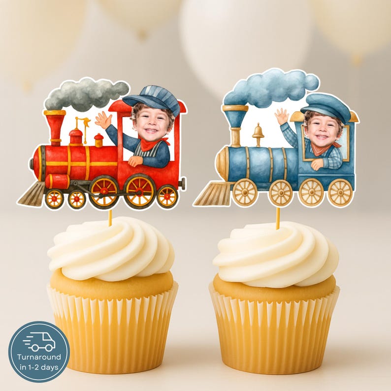 May include: Two cupcakes topped with personalized train-themed cake toppers. One topper features a red steam engine with a child's photo, and the other features a blue steam engine with a child's photo. Both trains have smoke clouds.
