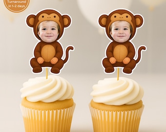 Op de afbeelding: Twee cupcakes met gele vormpjes en witte glazuur. Elke cupcake is versierd met een aap-thema decoratie met het gezicht van een kind. De decoraties zijn bruin en beige. De afbeelding bevat een cirkelvormige afbeelding met tekst.
