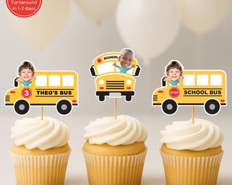 May include: Three cupcakes topped with yellow school bus toppers featuring children's faces. The toppers are yellow with black wheels and the text "THEO'S BUS" and "SCHOOL BUS". The cupcakes have white frosting.