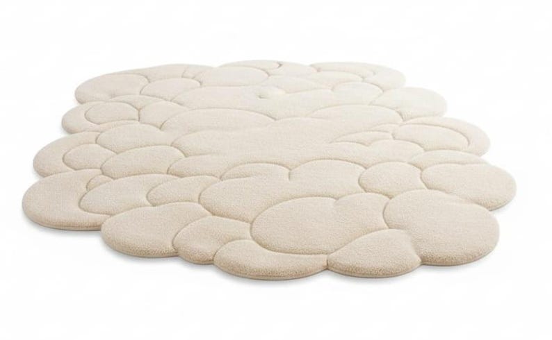 Puede incluir: Una alfombra beige con forma de nube y superficie texturizada. La alfombra est&aacute; compuesta por m&uacute;ltiples formas redondeadas e interconectadas, creando una apariencia suave y afelpada. La alfombra est&aacute; dise&ntilde;ada para la decoraci&oacute;n del hogar y a&ntilde;ade un toque de confort a cualquier habitaci&oacute;n.