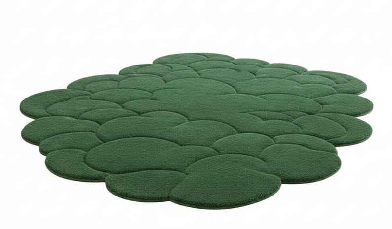Puede incluir: Una alfombra verde con forma de nube y superficie texturizada. La alfombra est&aacute; formada por m&uacute;ltiples formas redondeadas interconectadas, creando un dise&ntilde;o &uacute;nico y org&aacute;nico. El color es un verde intenso, y la alfombra est&aacute; sobre un fondo blanco.