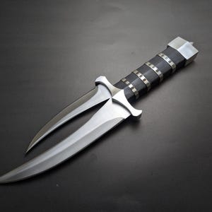 May include: A double-edged dagger with a polished steel blade and a black handle accented with silver bands. The dagger has a unique split blade design and a silver crossguard. The handle is capped with a silver end.
