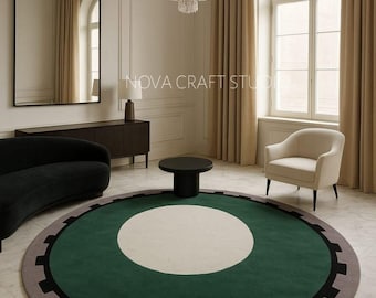 May include: A round area rug with a central white circle, surrounded by a green field, a gray border, and a black geometric pattern. The rug is in a room with a chandelier, a black sofa, and a white armchair.