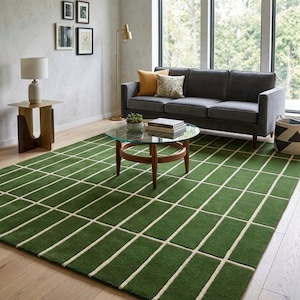 Pode incluir: Uma sala de estar moderna com um tapete verde com um padrão de grade, um sofá cinza e uma mesa de centro com tampo de vidro. O quarto é decorado com obras de arte emolduradas, uma luminária de chão e almofadas decorativas. O design do tapete são retângulos verdes separados por linhas creme.