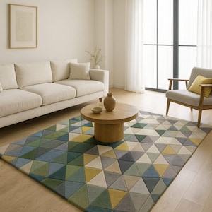 May include: A geometric patterned area rug with a modern design. The rug features a repeating pattern of triangles in shades of green, blue, yellow, and gray. The rug is placed in a living room setting with a sofa, chair, and coffee table. The text "NOVA CRAFT STUDIO" is visible.