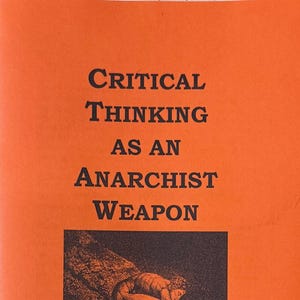 Może przedstawiać: Pomarańczowa broszura z tytułem "Myślenie krytyczne jako broń anarchistyczna". Broszura zawiera czarno-białą ilustrację osoby rysującej spiralę na ziemi.