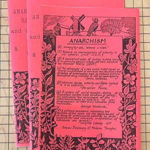 May include: A pink pamphlet with black text and illustrations. The pamphlet is titled "Anarchism" and defines the term in several ways. The text includes quotes from various authors, including Sebastian Faure, George Woodcock, and Emma Goldman.
