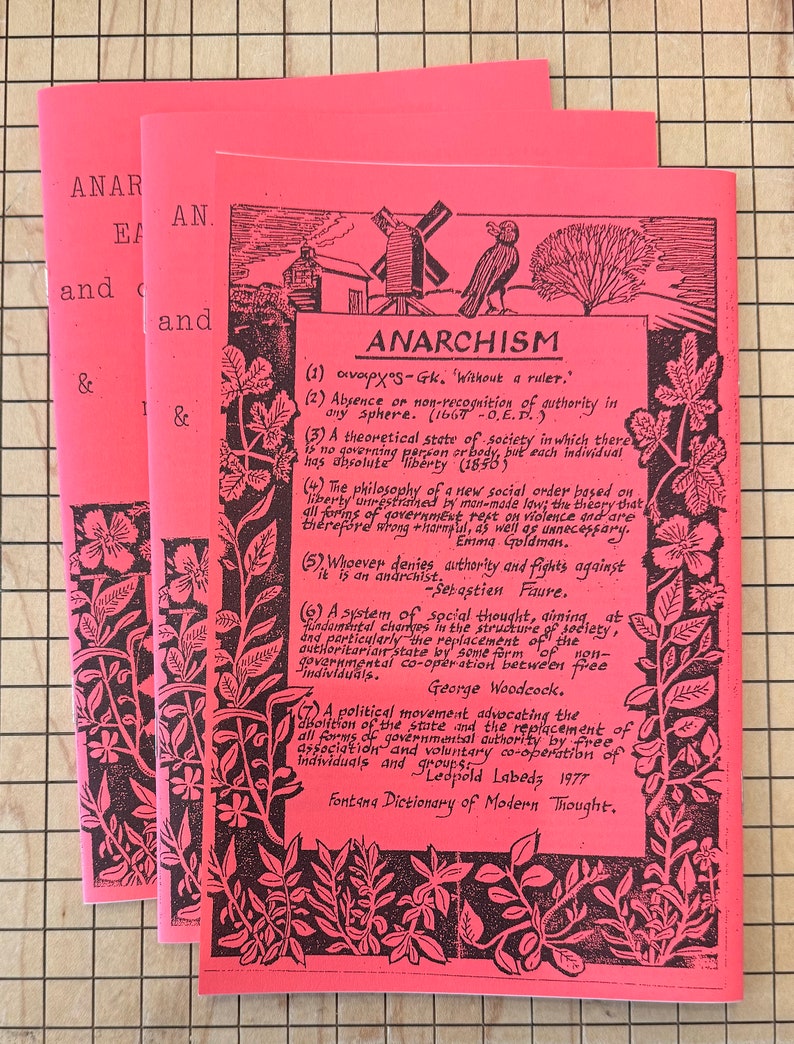May include: A pink pamphlet with black text and illustrations. The pamphlet is titled "Anarchism" and defines the term in several ways. The text includes quotes from various authors, including Sebastian Faure, George Woodcock, and Emma Goldman.