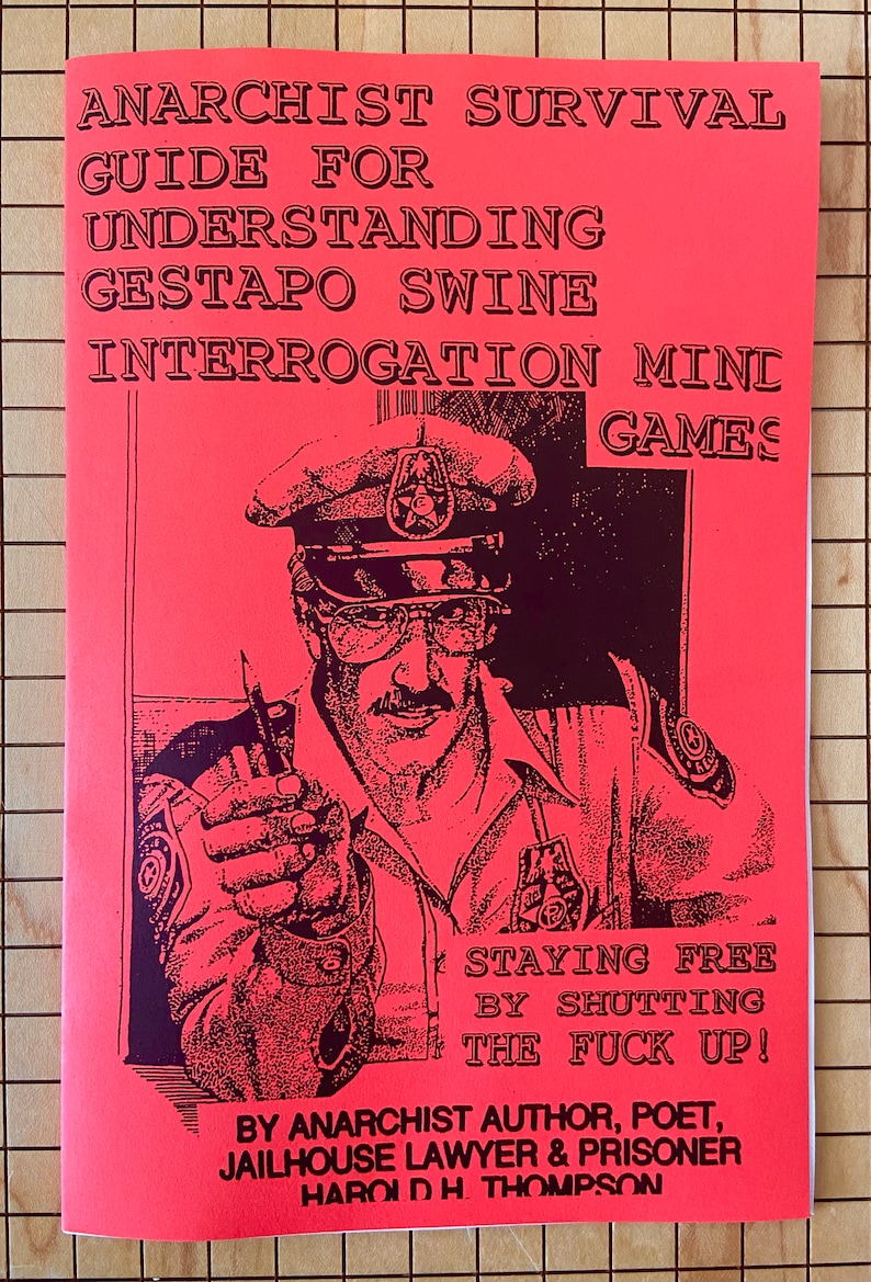 May include: A red pamphlet with black text titled "Anarchist Survival Guide for Understanding Gestapo Swine Interrogation Mini Games." The cover features a black and white illustration of a police officer with a stern expression, pointing a finger at the viewer. The text "Staying Free By Shutting The Fuck Up!" is printed below the illustration. The pamphlet is attributed to "Anarchist Author, Poet, Jailhouse Lawyer & Prisoner Harold H. Thompson."