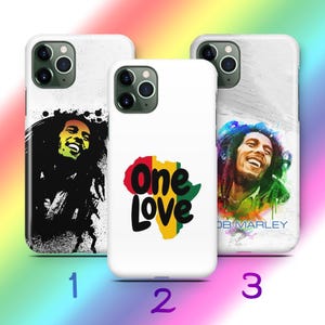 May include: Three white phone cases with different designs. One case features a black and yellow image of a smiling man. Another has the words "One Love" over a map of Africa. The third case has a colorful image of a smiling man.