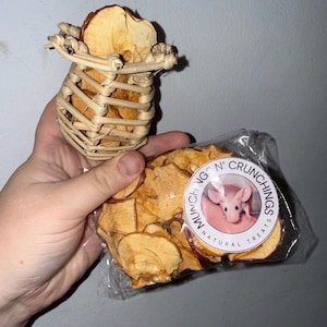 May include: A vine pot filled with dehydrated fruit slices and a bag of dehydrated fruit treats. The bag has a circular label with a pink mouse illustration and the text "Munch N' Crunchings Natural Treats".