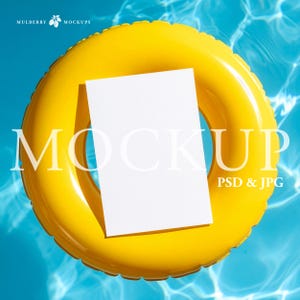 May include: A bright yellow inflatable pool ring floats in a pool of blue water. A white rectangular card rests on the ring. The word "MOCKUP" is printed in large white letters on the card and ring. The text "PSD & JPG" is printed in white.