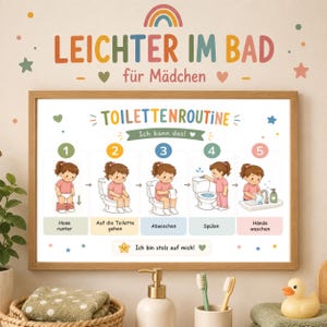 Op de afbeelding: Een ingelijste instructieposter getiteld LEICHTER IM BAD für Mädchen met een toiletroutine in vijf stappen. De kaart bevat genummerde illustraties van een kind dat de broek naar beneden doet, op het toilet zit, afveegt, doortrekt en handen wast.