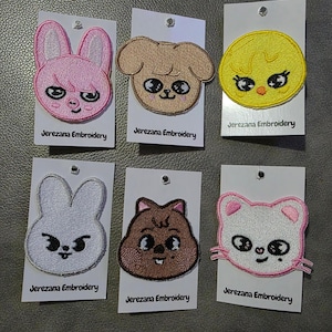 Puede incluir: Parches bordados con caras de animales de dibujos animados: un conejo rosa, un perro marrón, un pollito amarillo, un conejo blanco, un gato marrón y un gato rosa. Cada parche está en una tarjeta blanca con "Jerezana Embroidery".