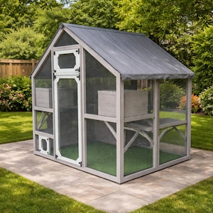 May include: A gray wooden outdoor cat enclosure with a mesh screen, a gray roof, and a green floor. The enclosure has multiple levels and a door with white trim. It is set on a concrete patio surrounded by grass and trees.