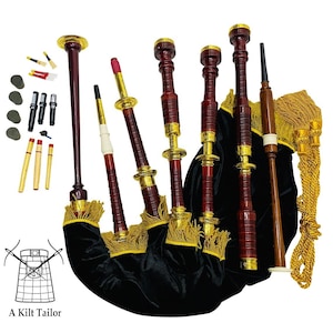 Puede incluir: Un juego completo de gaita con una bolsa de terciopelo negro, adornos dorados y tubos de madera. El juego incluye varios accesorios y el texto "A Kilt Tailor" en la parte inferior.