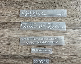 May include: Five white vinyl adhesive decals featuring text in various fonts. The decals display the Arabic Bismillah, the names Talha & Zohra, the quote AND HE PLACED BETWEEN YOU AFFECTION AND MERCY, the citation QURAN (30:21), and the date 22.03.26.