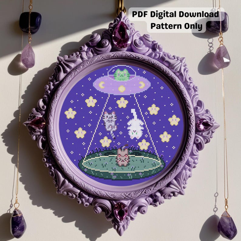 May include: A framed cross-stitch pattern with a purple border and a circular design. The design features a UFO abducting a cat and a bunny, with stars and a planet in the background. The text "PDF Digital Download Pattern Only" is at the top.