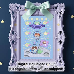 May include: A framed cross-stitch design featuring a space-themed illustration with cartoon cats in spacesuits and a UFO. The design is in a light blue color scheme with stars and planets. The frame is lavender with a green bow.