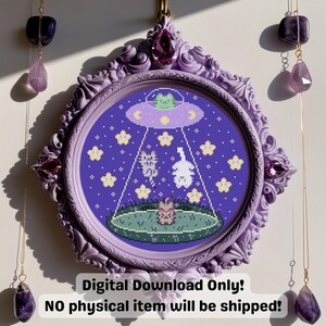 May include: A framed cross-stitch design featuring a purple background with a UFO abducting a cat, a bunny, and a pig. The frame is ornate, lavender-colored, and has a decorative top. The text at the bottom reads "Digital Download Only! NO physical item will be shipped!"
