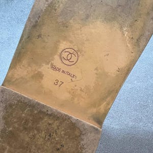 May include: Close-up of the sole of a sandal. The sole is a light brown color with a worn appearance. The brand logo is visible, along with the text "MADE IN ITALY" and the size "37".