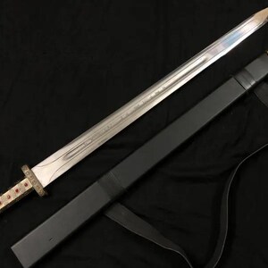 May include: A silver sword with a decorative gold and red handle and a black sheath. The sword's blade is long and sharp, and the sheath has a strap for carrying. The sword is likely a replica or decorative item.