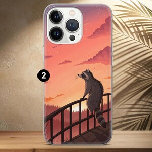 May include: A phone case featuring a raccoon on a bridge, set against a sunset sky. The raccoon is gray and white, with a striped tail. The background includes a forest and a vibrant orange and pink sky.