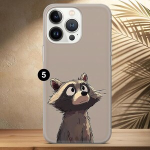 May include: A clear phone case featuring a cartoon raccoon illustration. The raccoon is depicted with a curious expression, in shades of brown, gray, and white. The number "5" is printed in black on the case.