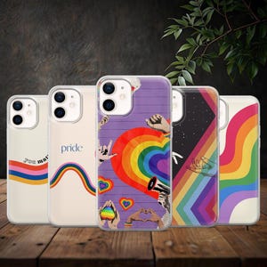 Op de afbeelding: Vijf doorzichtige telefoonhoesjes met kleurrijke ontwerpen. Eén hoesje heeft een regenboog en de woorden "You matter". Een andere zegt "pride" met een regenboog. Andere hoesjes tonen harten, handen en een regenbooghart.
