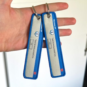 May include: Two blue and gray keychains with the text "Windows XP" and "Task failed successfully." The keychains have a silver key ring and a red "X" icon. The keychains are rectangular and have a blue border.