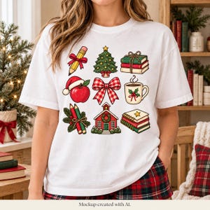 May include: A white short-sleeve t-shirt featuring a grid of nine colorful illustrations including a pencil, a Christmas tree, a stack of books, an apple with a Santa hat, a red plaid bow, a mug, pencils, a schoolhouse, and a notebook.