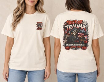 Puede incluir: Una camiseta de color crema con un pequeño gráfico en el pecho izquierdo y un gráfico grande en la espalda. El diseño trasero muestra un esqueleto con uniforme médico sosteniendo unas tijeras, con el texto "TRICK OR TRAUMA" y "EMERGENCY DEPARTMENT LEVEL ONE EST. 24/7" en rojo y negro.