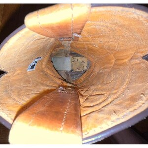 May include: A top-down view into the interior of a brown leather cowboy boot. The lining is a light tan color with visible stitching patterns along the shaft. Two leather pull straps extend upward from the opening, and a small white tag is visible.