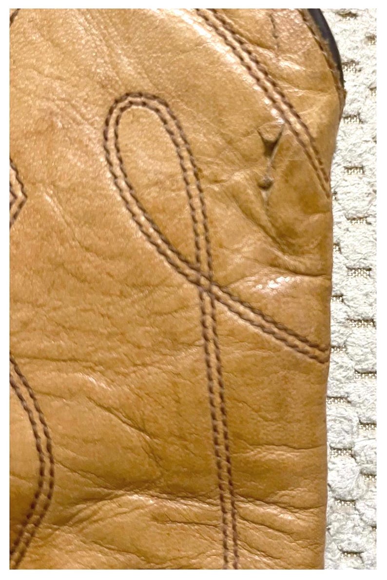 May include: A tan leather boot featuring a textured surface with visible grain and decorative stitching patterns. The stitching forms curved, loop-like designs across the leather material, highlighting the construction and detail of the footwear.