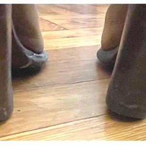May include: A pair of dark brown wedge heels featuring a smooth, solid-colored exterior. The shoes have a thick, tapered wedge heel design that provides a stable base, with the back of the heel clearly visible as it rests on a wooden floor surface.