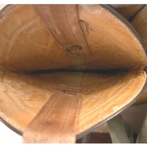 May include: The interior view of a tan leather boot showing the light brown lining, visible stitching patterns along the shaft, and two vertical pull straps attached to the top edge of the opening, revealing the construction of the footwear.