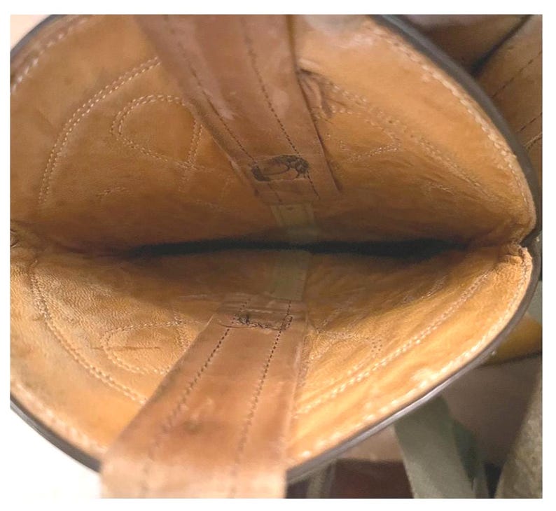 May include: The interior view of a tan leather boot showing the light brown lining, visible stitching patterns along the shaft, and two vertical pull straps attached to the top edge of the opening, revealing the construction of the footwear.