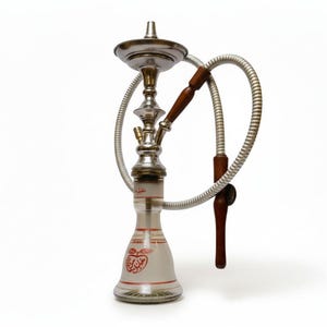 May include: A silver hookah with a glass base, featuring red Arabic script and apple designs. It has a silver stem, a wooden handle, and a flexible silver hose. The hookah is set against a white background.