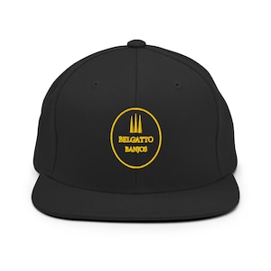 Può includere: Un cappellino da baseball nero con un logo circolare giallo ricamato sul davanti. Il logo contiene tre linee verticali sopra il testo BELGATTO BANJOS, il tutto racchiuso in un sottile cerchio giallo. Il cappellino ha una visiera piatta e rigida.